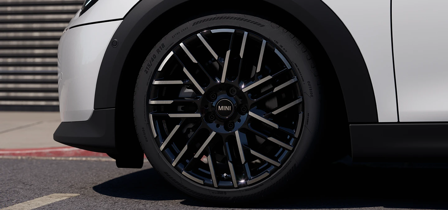 Primer plano del MINI Cooper 5 puertas en Nanuq White con llantas bitono Night Flash.