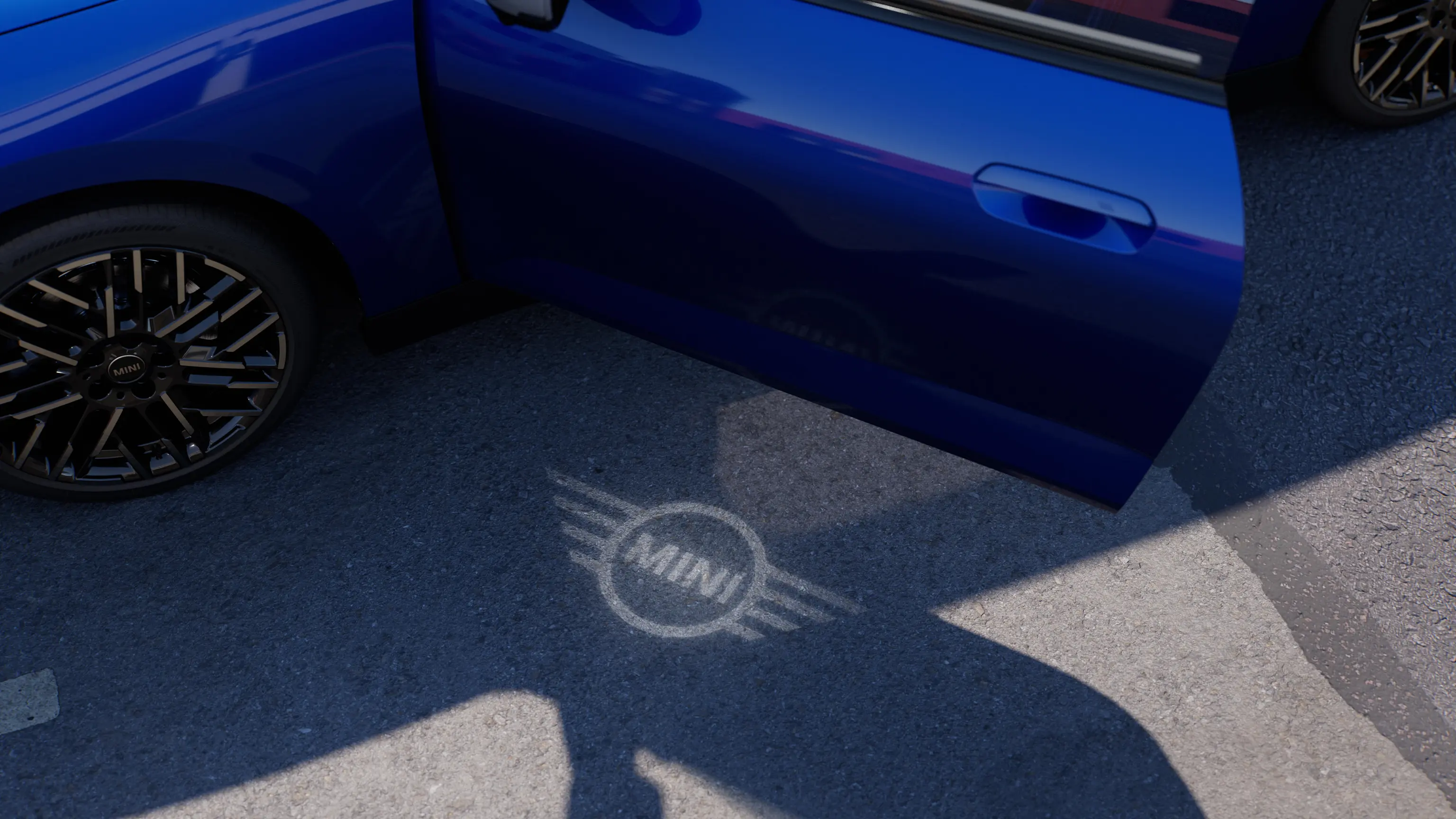 Vista exterior de un MINI Cooper 100 % eléctrico con la puerta abierta mostrando la luz de bienvenida del logotipo de MINI en el suelo