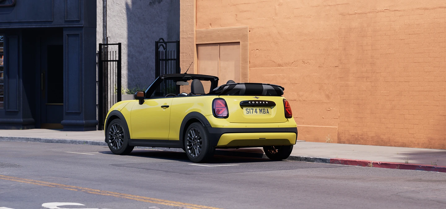 Vista trasera izquierda del MINI Cooper Cabrio en Sunnyside Yellow aparcando.