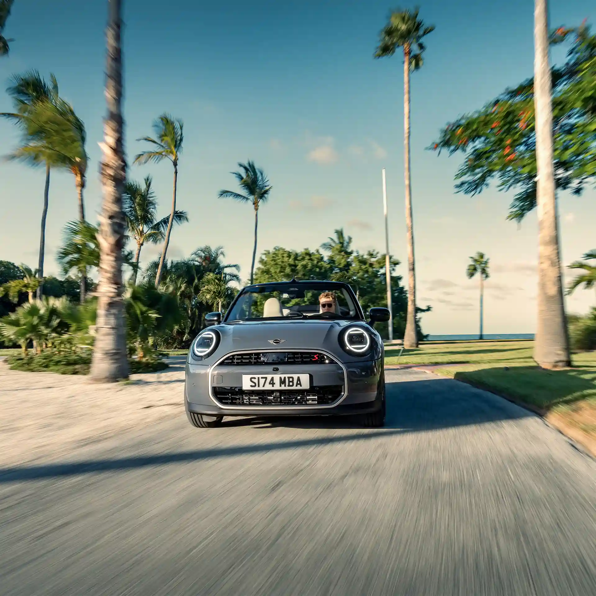 Vista frontal de un MINI Cooper Cabrio en Copper Grey conduciendo por la calle