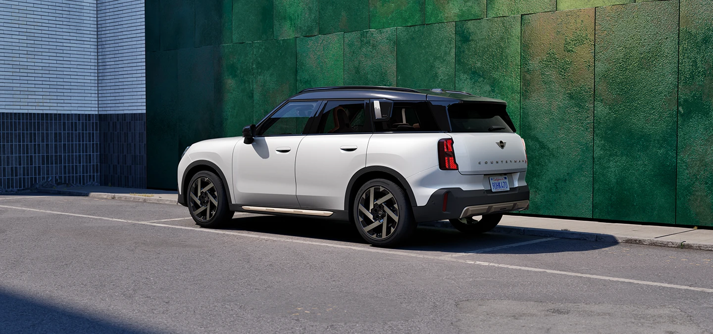 Vista trasera lateral del MINI Countryman en Nanuq White con techo negro en una calle.