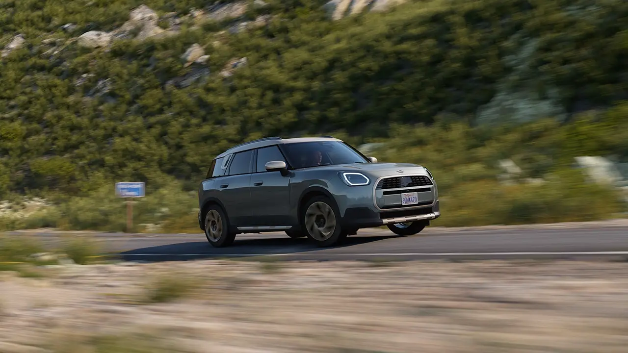 Vista del MINI Countryman en Smokey Green con acabado Favoured conduciendo por el campo