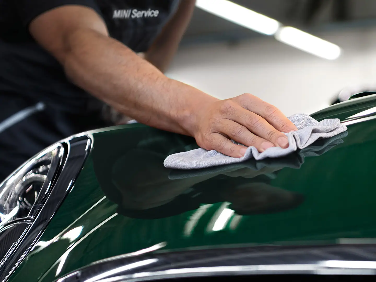 Limpieza y cuidados MINI: un técnico pule la superficie de un MINI de color Racing Green.