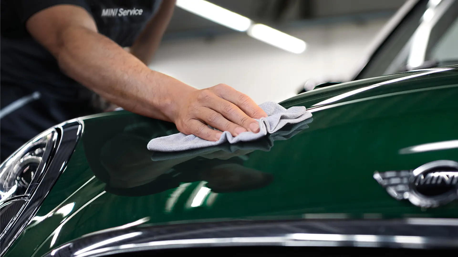 Limpieza y cuidados MINI: un técnico pule la superficie de un MINI de color Racing Green.
