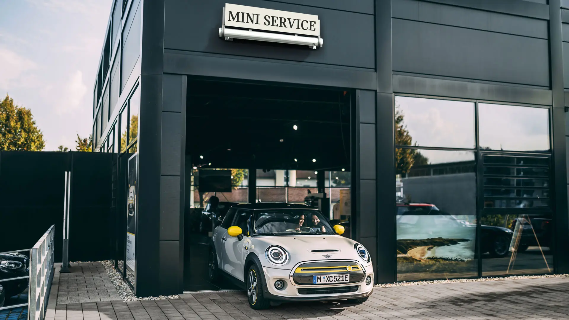 Las instalaciones de un Taller autorizado MINI con una clienta que conduce su nuevo MINI Electric hasta la explanada