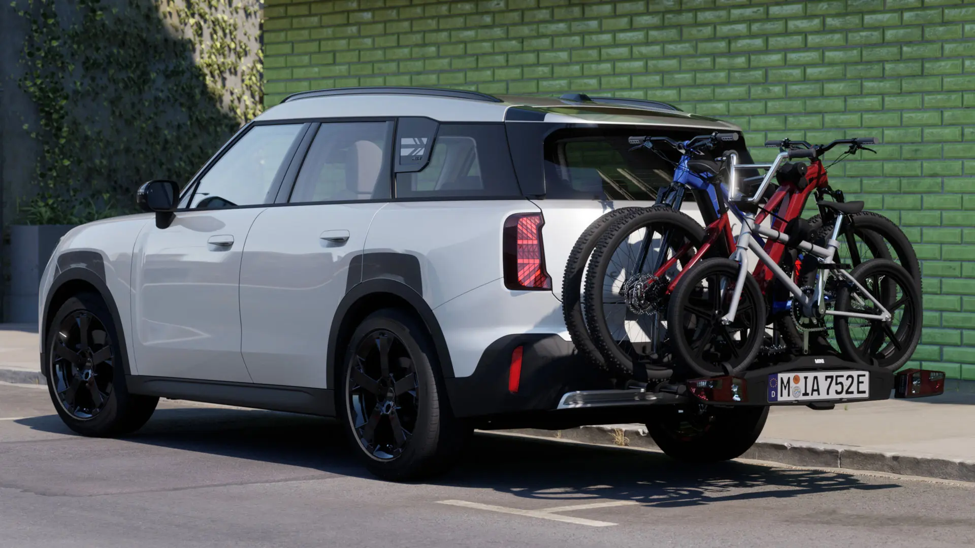 Un MINI Aceman en Nanuq White equipado con el portabicicletas trasero MINI Pro 3.0, cargado con dos bicicletas de montaña y una bicicleta infantil.