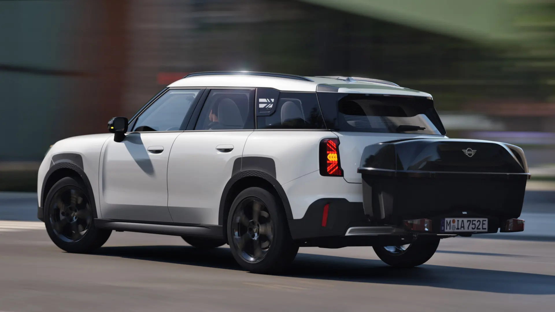 Vista lateral trasera del MINI Aceman en Nanuq White equipado con un portabicicletas trasero MINI cargado con la caja trasera MINI. 