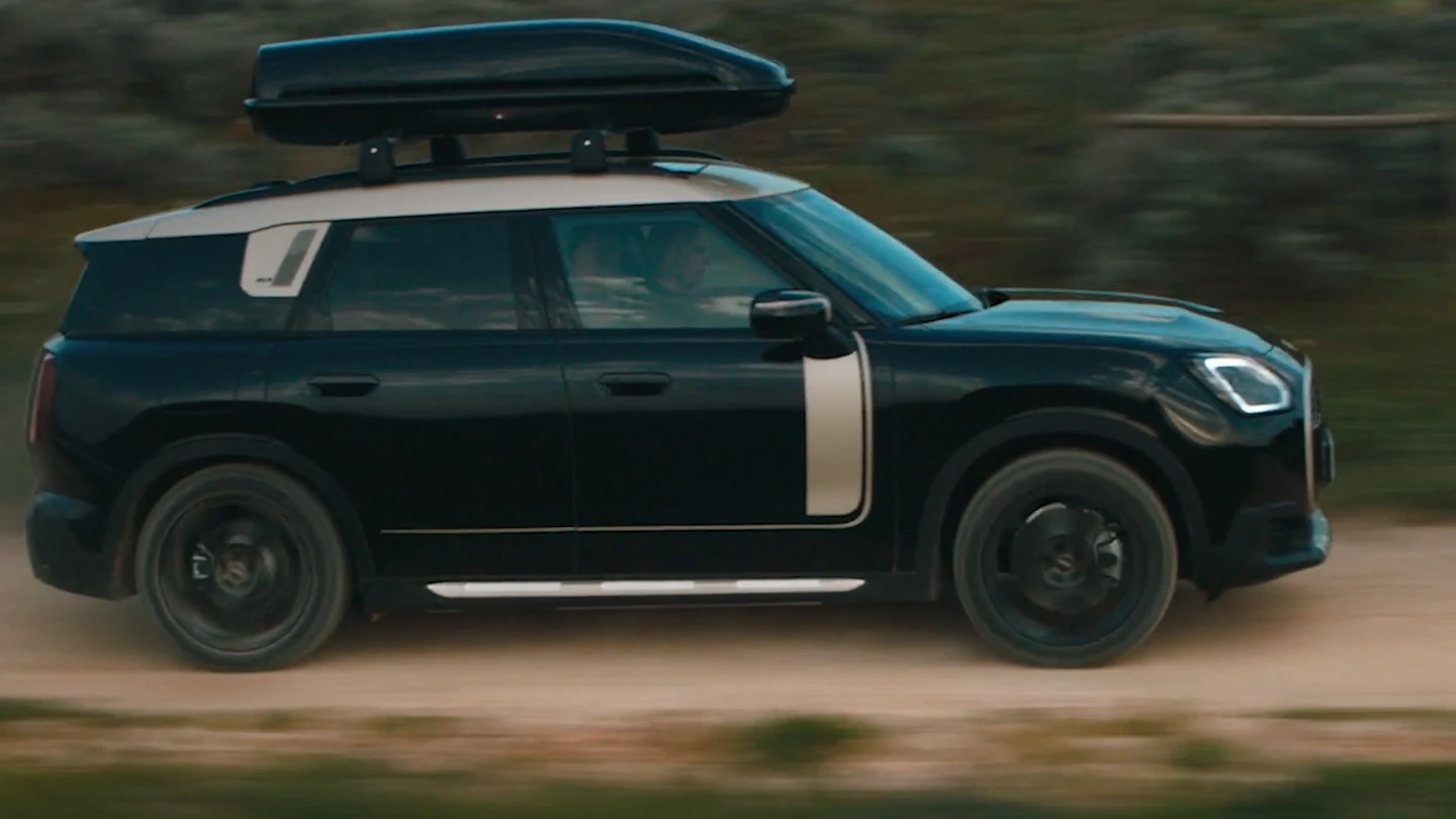MINI Countryman en Midnight Black metalizado con llantas John Cooper Works Runway Spoke de 19" en negro, conduciendo campo a través. 