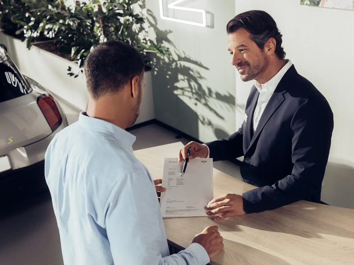 Un asistente de servicio del Agente MINI asesorando a un cliente sobre las opciones del seguro de neumáticos MINI.