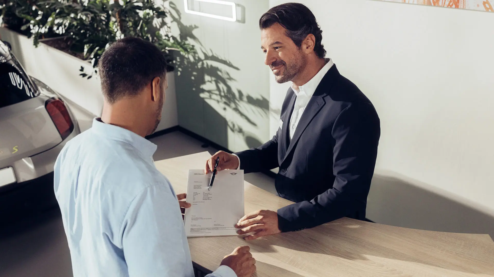 Un asistente de servicio del Agente MINI asesorando a un cliente sobre las opciones del seguro de neumáticos MINI.