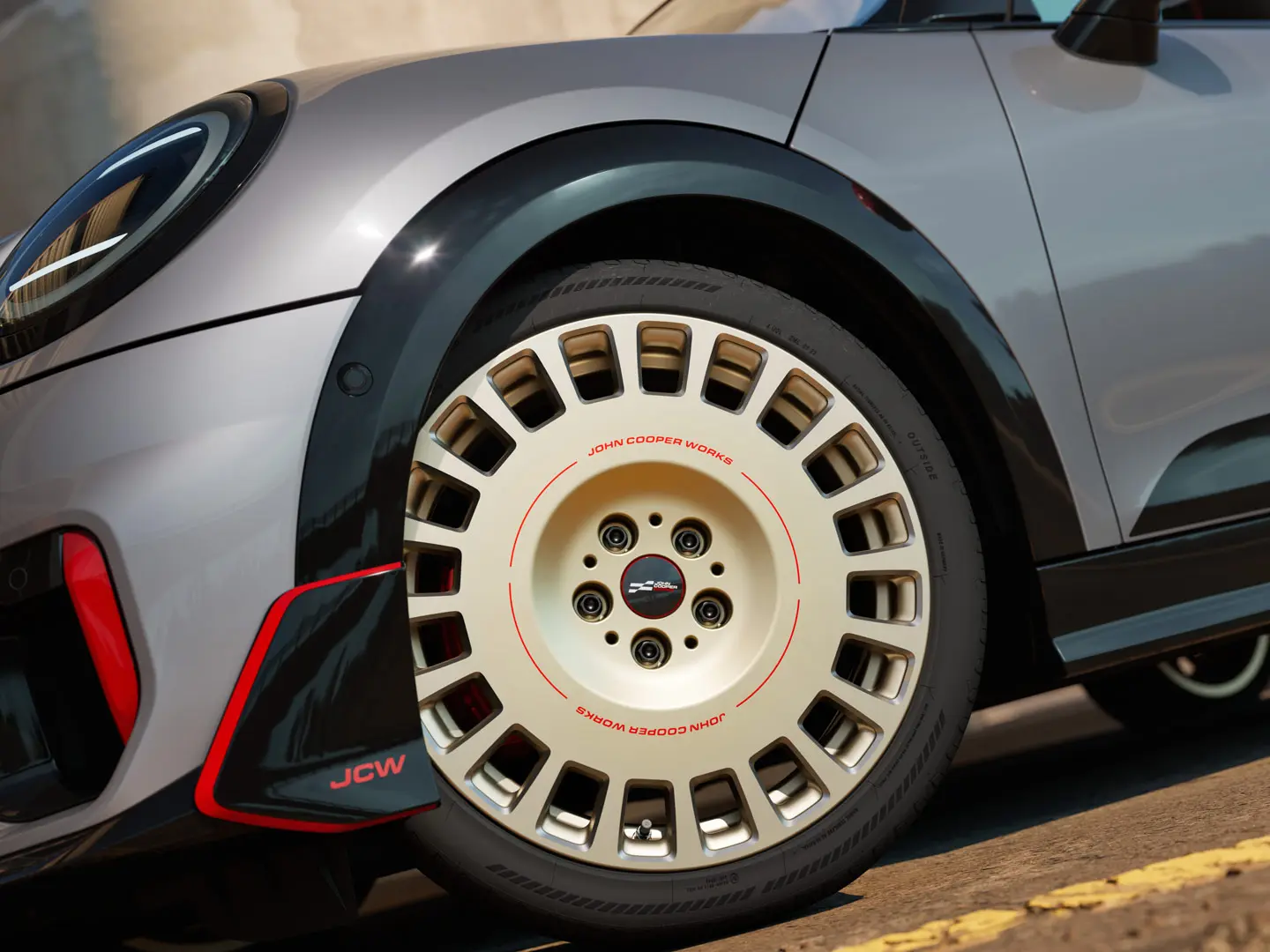 Primer plano de los detalles de una llanta JCW Rallye Spoke 964 de 18" en Bicolour Vibrant Silver y diamantada y winglet delantero.