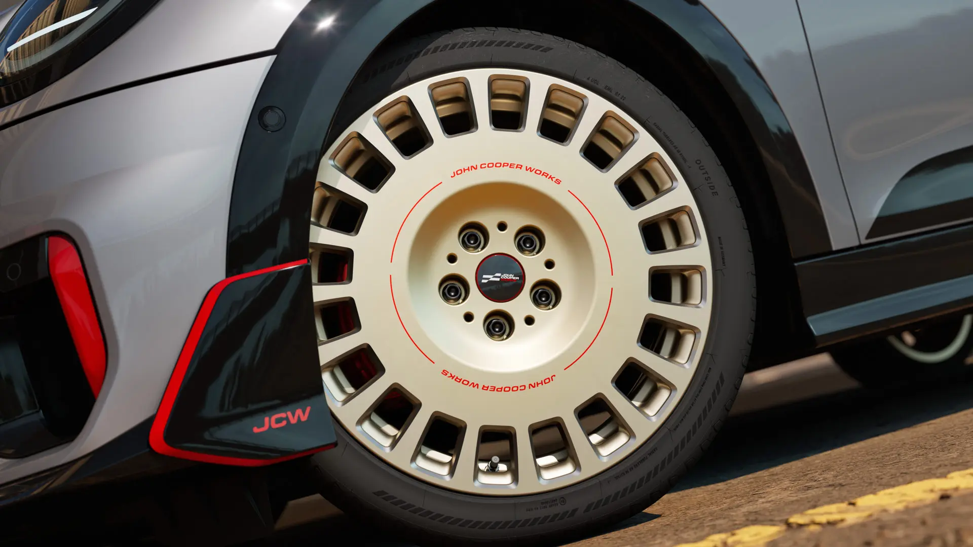 Primer plano de los detalles de una llanta JCW Rallye Spoke 964 de 18" en Bicolour Vibrant Silver y diamantada y winglet delantero.