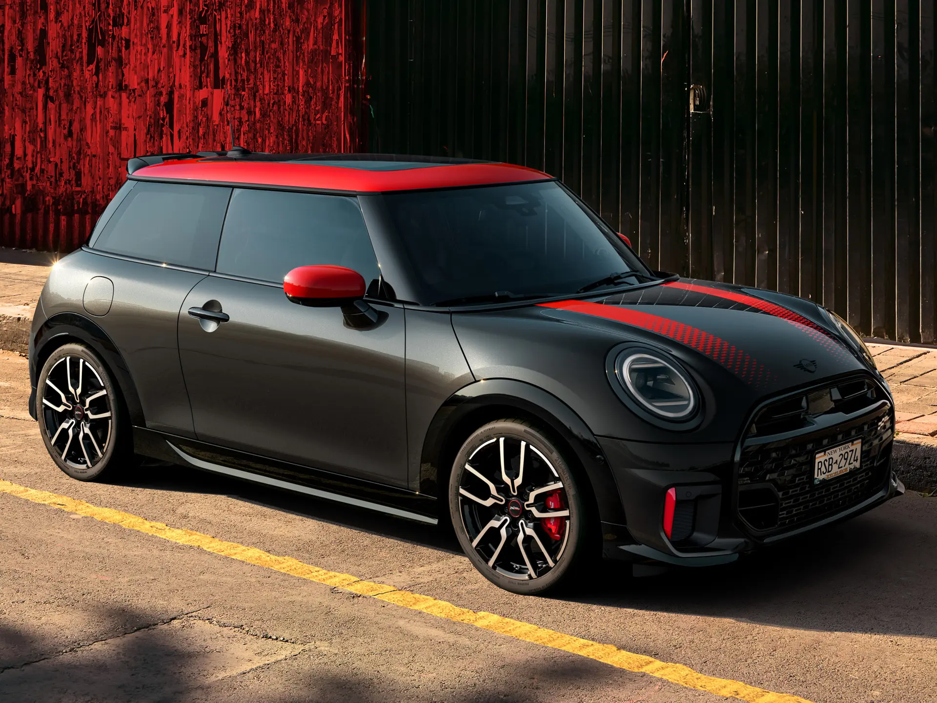 MINI John Cooper Works 3 Puertas en Midnight Black con techo y cubiertas de retrovisor en Chili Red y franjas deportivas Chili Red, vista lateral, aparcado en la calle.