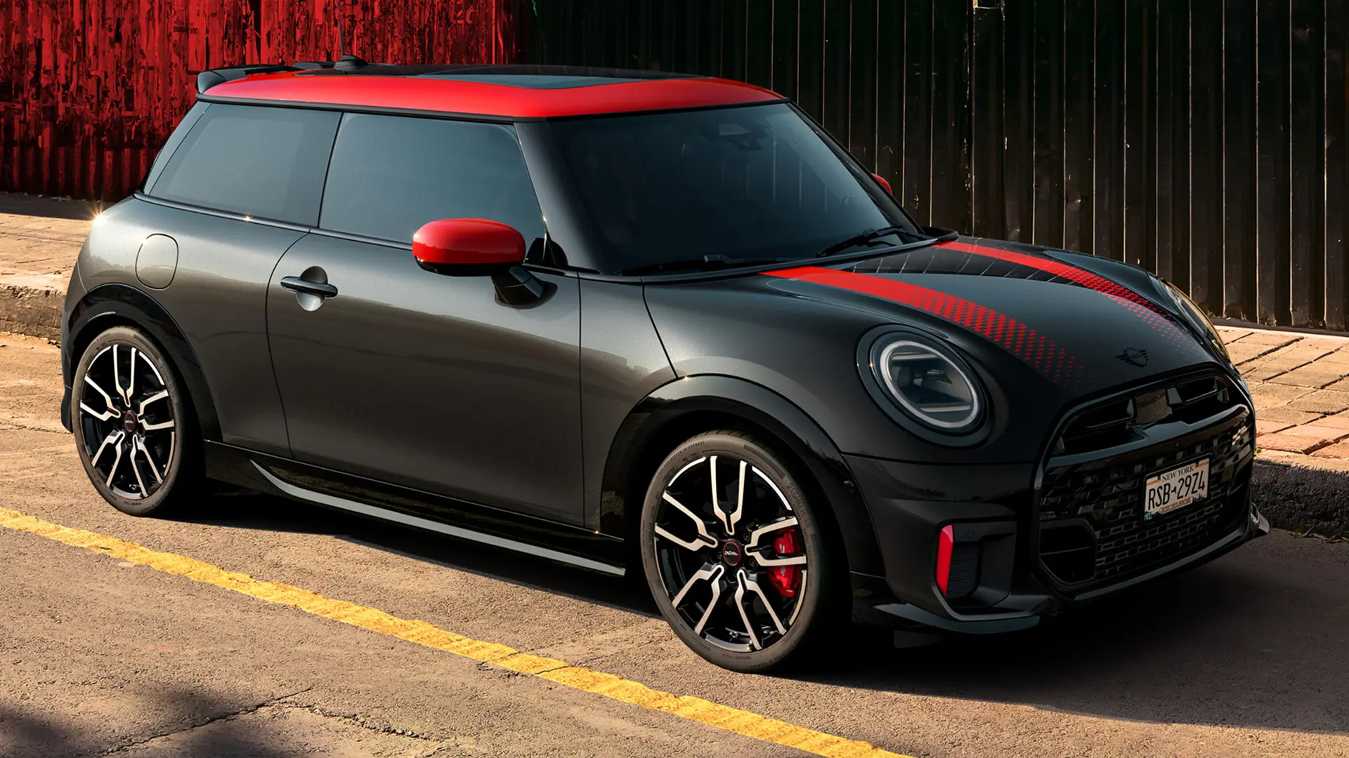 MINI John Cooper Works 3 Puertas en Midnight Black con techo y cubiertas de retrovisor en Chili Red y franjas deportivas Chili Red, vista lateral, aparcado en la calle.