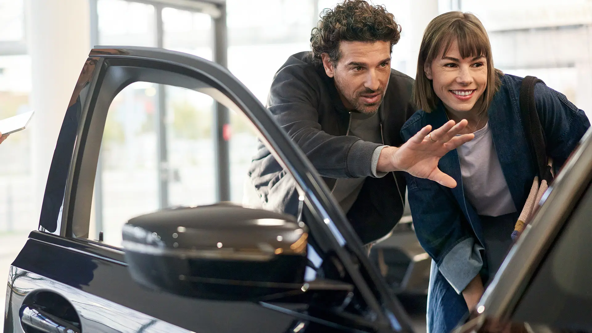 Un MINI en un concesionario MINI y un agente aconsejando a un cliente y explicándole las prestaciones del interior.