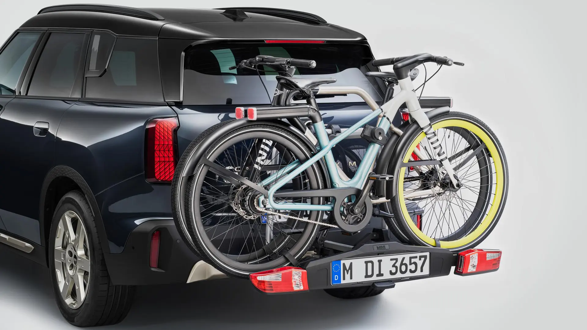 MINI Countryman en Black equipado con un soporte posterior para bicicletas que carga dos bicicletas de montaña, vista trasera.