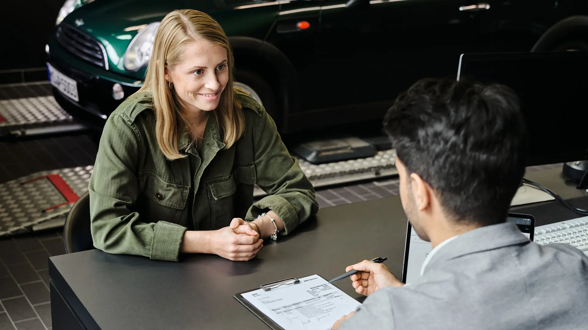 Un agente de un MINI Centre aconseja a su cliente sobre las diferentes opciones de mantenimiento sentados a una mesa.