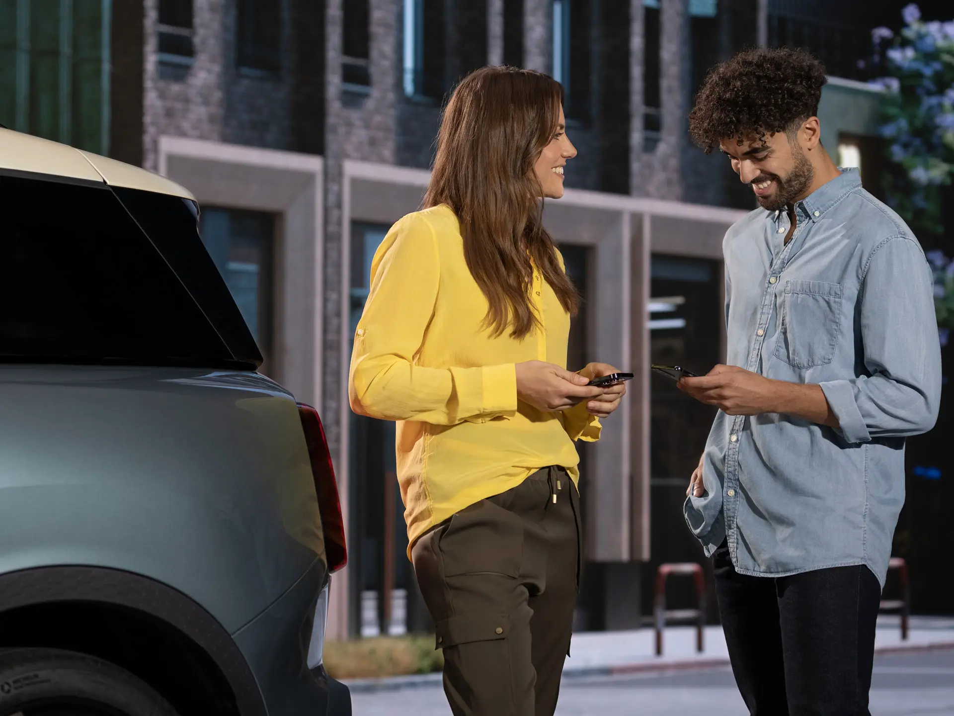 Un hombre y una mujer de pie junto a un MINI, contactando con un servicio técnico de MINI utilizando sus teléfonos.